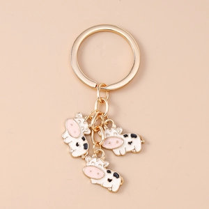 Detailed close-up of cartoon cow keychains with gold-plated rings and enamel pendants