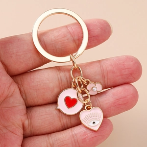 Detail of pink enamel heart and flower pendants on a gold-tone metal keychain