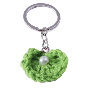 Nahaufnahme eines grünen gestrickten Herz-Schlüsselanhängers mit Perle und Ring