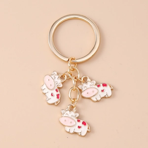 Detail of cute cartoon cow pendants with gold metal rings and enamel heart spots