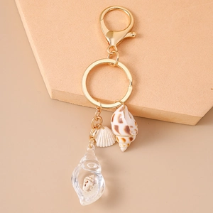 Close-up of golden summer beach keychain with shell and luminous conch pendant charms