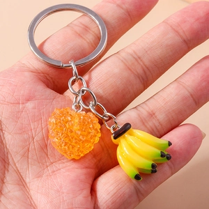 Porte-clés fruits avec cœur orange et breloque banane présenté dans une main