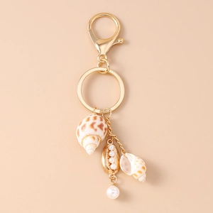 Détail du pendentif coquillage doré avec perles et conque sur un porte-clés marin