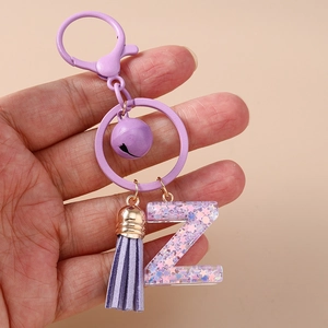 Détail du porte-clés lettre Z en résine violette avec paillettes, clochette et gland