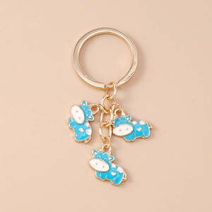 Detailed view of three blue and white enamel cow charms on a golden keychain