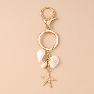 Détail d'un porte-clés marin doré avec de vrais coquillages et un pendentif étoile de mer