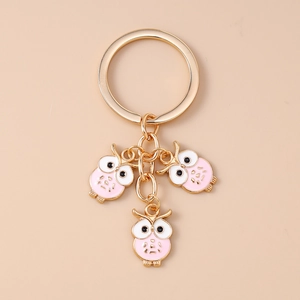 Détail des pendentifs hibou en émail rose et blanc avec anneau doré