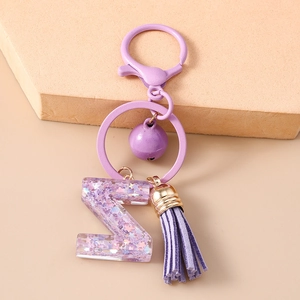 Détail d'un porte-clés lettre Z en résine violette avec gland et petite clochette
