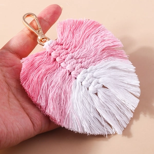 Detail of pink and white handmade woven tassel fan charm with golden metal clasp