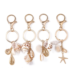 Lot de porte-clés coquillage doré avec étoile de mer, perles et conques sur fond blanc épuré