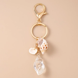 Detail of nautical keychain with gold clasp, natural seashells, and clear resin conch charm