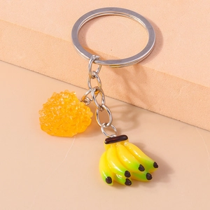Vue détaillée de pendentifs banane et fruits artificiels sur un porte-clés en métal argenté