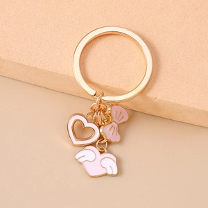 Close-up of pink heart keychain with golden metal ring and enamel charms in soft light
