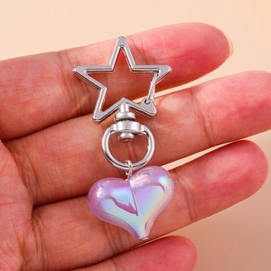 Detailed view of purple holographic heart keychain with silver star clasp held by hand