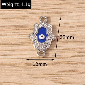 Macro shot of silver Hamsa Hand charm with blue Evil Eye and rhinestones on wood