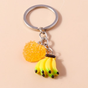 Détail du porte-clés argenté avec breloques bananes jaunes et pendentif fruit orange