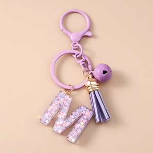 Détail du porte-clés lettre M à paillettes violettes avec pompon en cuir et clochette