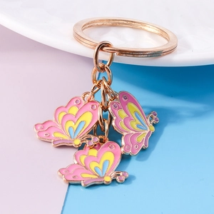 Dettaglio dei ciondoli a farfalla in smalto rosa e blu su un portachiavi in oro rosa