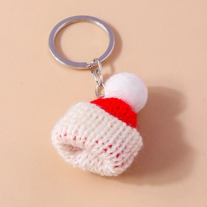 Creative knitted Christmas hat keychain with red and white pompom on a warm background