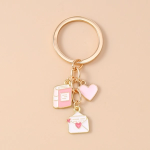 Detail of gold alloy keychain with pink book, heart, and white enamel envelope charms