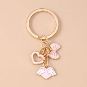 Detailed view of pink enamel heart and bow charms on a gold-plated metal keychain
