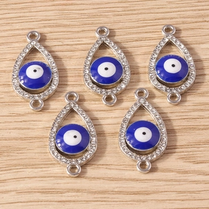Detailed view of silver evil eye charms with white rhinestones on wood surface