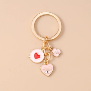 Detail of golden heart keychain featuring pink enamel charms and a pearl flower pendant