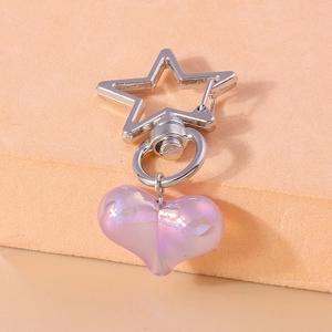 Macro shot of silver star clasp and iridescent purple heart pendant on jewelry stand