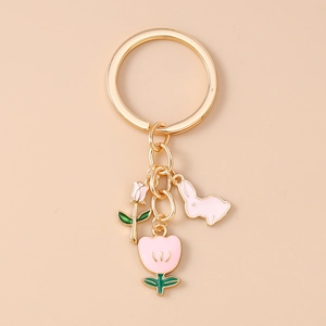 Detail of pink enamel bunny and tulip charms on a golden metal keychain with heart motifs