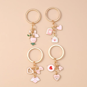 Detailed close-up of gold-plated rabbit and tulip enamel keychains with pink charm accents