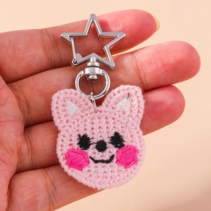 Gros plan du porte-clés Cooky en tricot rose avec un fermoir métallique argenté en étoile