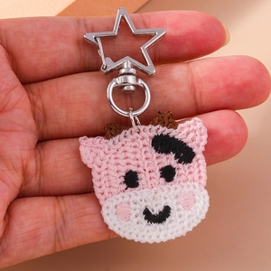 Détail d'un porte-clés vache rose au crochet fait main avec un clip étoile en argent