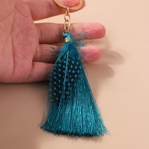 Close-up of bohemian tassel keychain with blue natural feather and gold ring