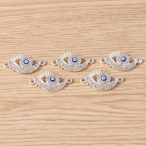 Detail showing five silver Evil Eye palm charms with rhinestones on wood surface