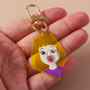Cartoon girl blowing bubbles acrylic keychain with gold metal clasp on beige background