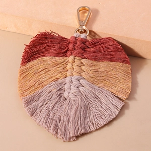 Detail view of handmade woven leaf keychain with boho style tassels and golden lobster clasp