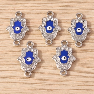 Detailed macro view of Hamsa Hand and Evil Eye charms with blue enamel and rhinestones