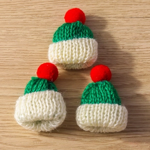 Three mini knitted Christmas hat charms with festive red, green and white yarn texture