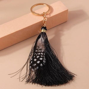 Detail of bohemian tassel keychain with black fibers and natural guinea fowl feathers