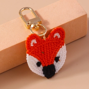 Close-up of handmade knitted orange fox keychain with a gold metal clasp for bags