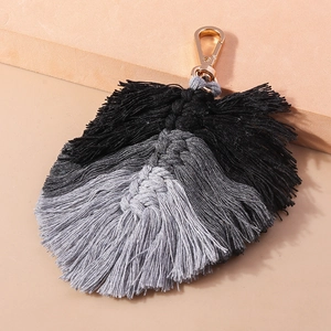 Close-up of bohemian hand-woven feather tassel keychain with grey gradient and gold clasp
