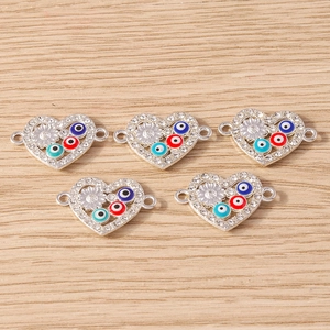 Detail showing heart-shaped evil eye connectors with rhinestones on wood surface