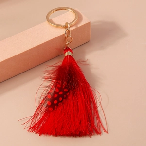 Detail view of Bohemian red tassel keychain with gold ring and polka dot feather