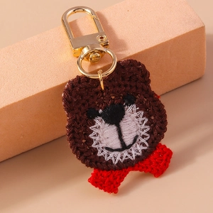 Detailed view of a handmade brown crochet bear pendant with a cute red bow tie and gold clasp