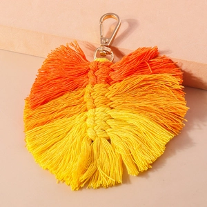 Detail of handmade yellow-orange gradient woven feather keychain with gold metal clasp