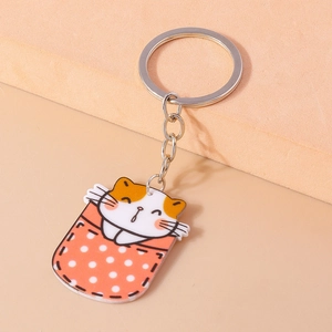 Détail du porte-clés chat en acrylique avec motif de poche à pois rouges et anneau métal
