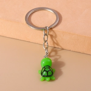 Detailed close-up of a cute green turtle keychain with silver metal ring on a neutral base