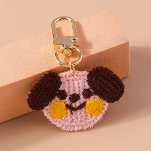 Macro shot of handmade crochet puppy keychain with pink ears and golden clasp detail