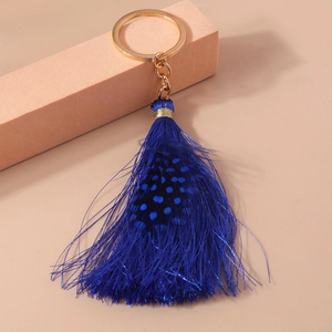 Close-up of deep blue tassel keychain with gold ring and spotted decorative feathers