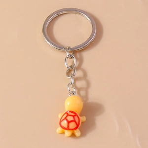 Detailed view of a cute yellow resin turtle keychain with red patterned shell on silver ring